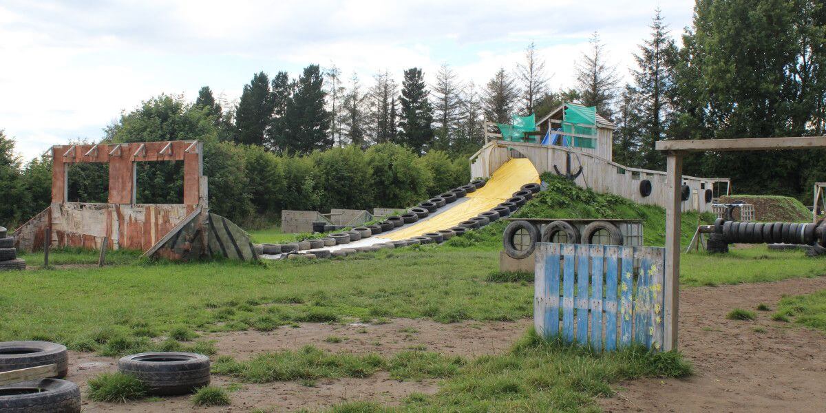 Wooden obstacles and tyres with a water slide forming a military style assault course