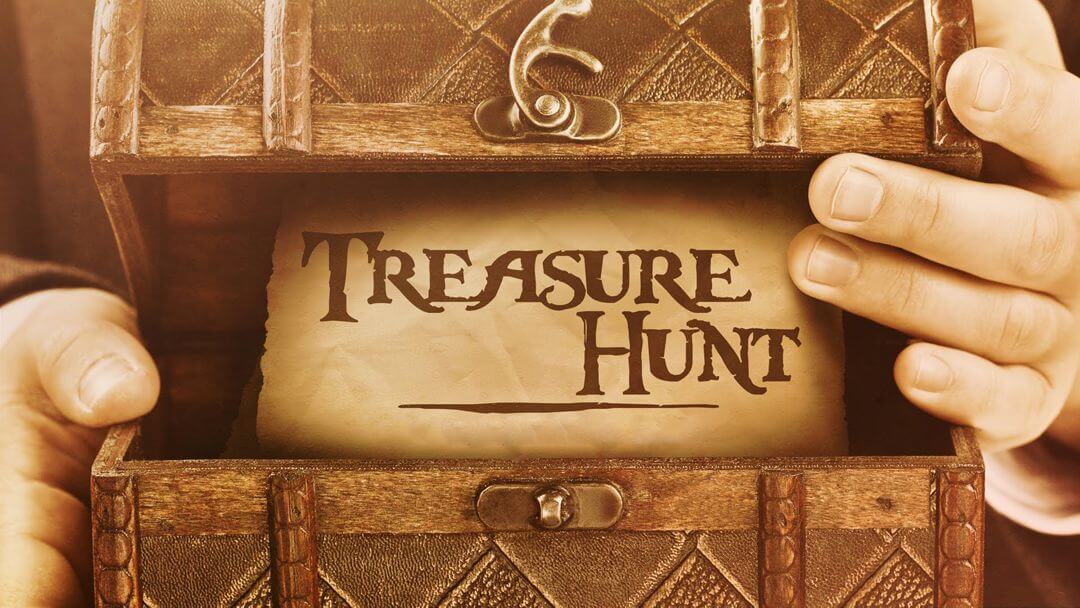 Hen Parties Kilkenny Hands holding a half-open treasure chest revealing a scroll with the words Treasure Hunt on it.