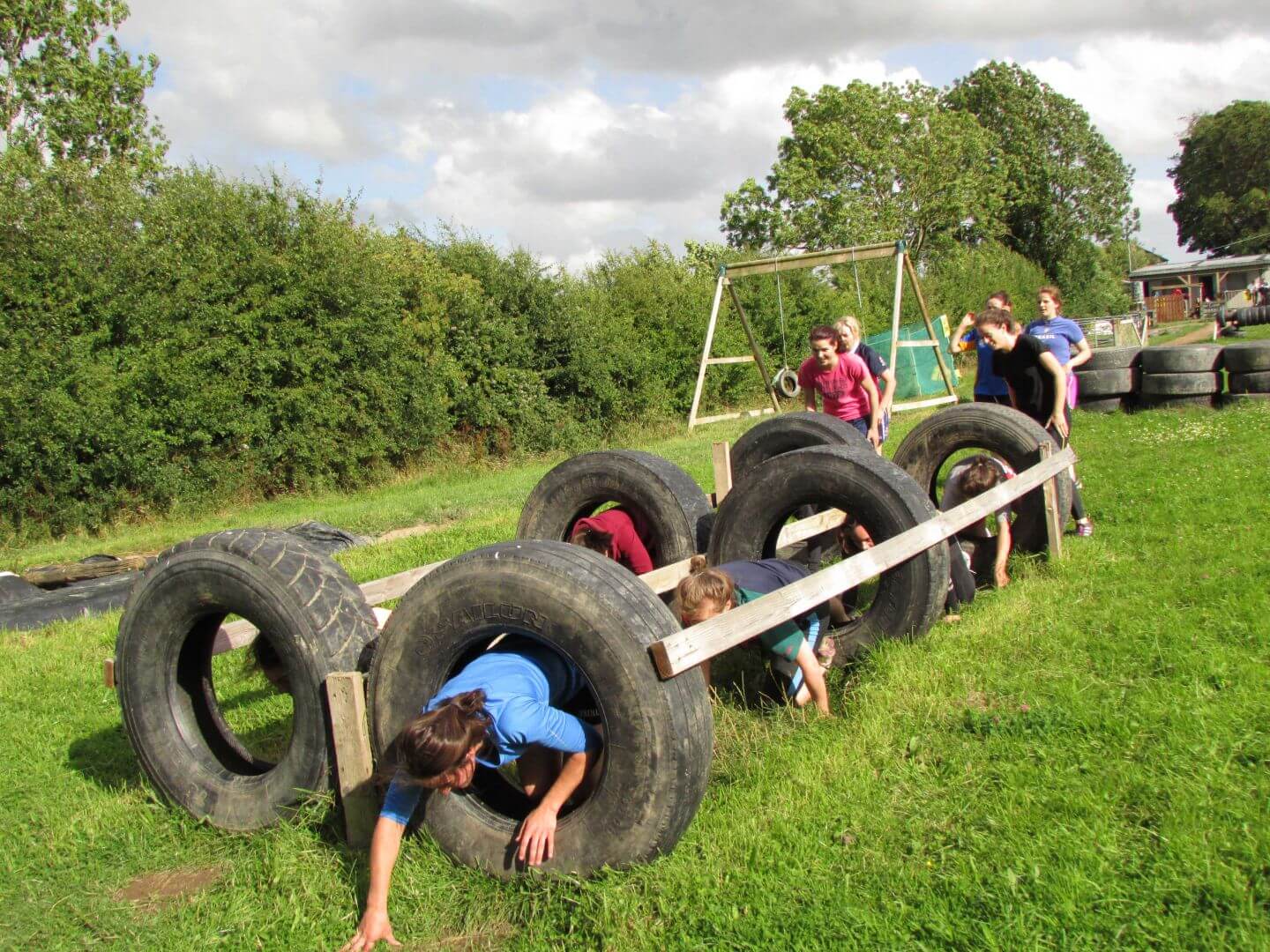 Hen Parties Kilkenny A group of girls on a hen party crawl through a tyre obstacle whilst others watch.