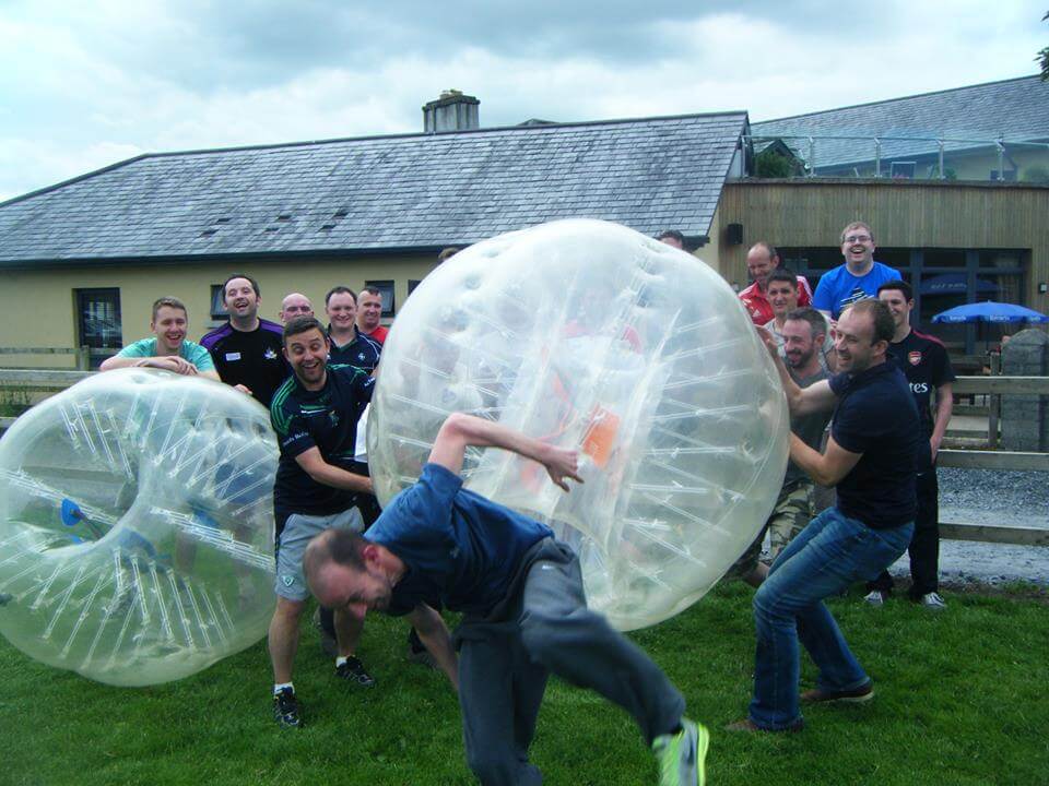 Two men try to put a bubble ball over another man's head while taking part in bubble soccer during a stag party.
