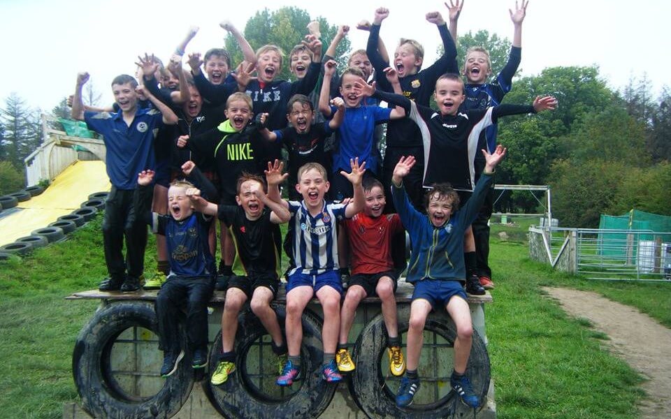 A group of young boys posing for a photo and cheering whilst standing on an obstacle